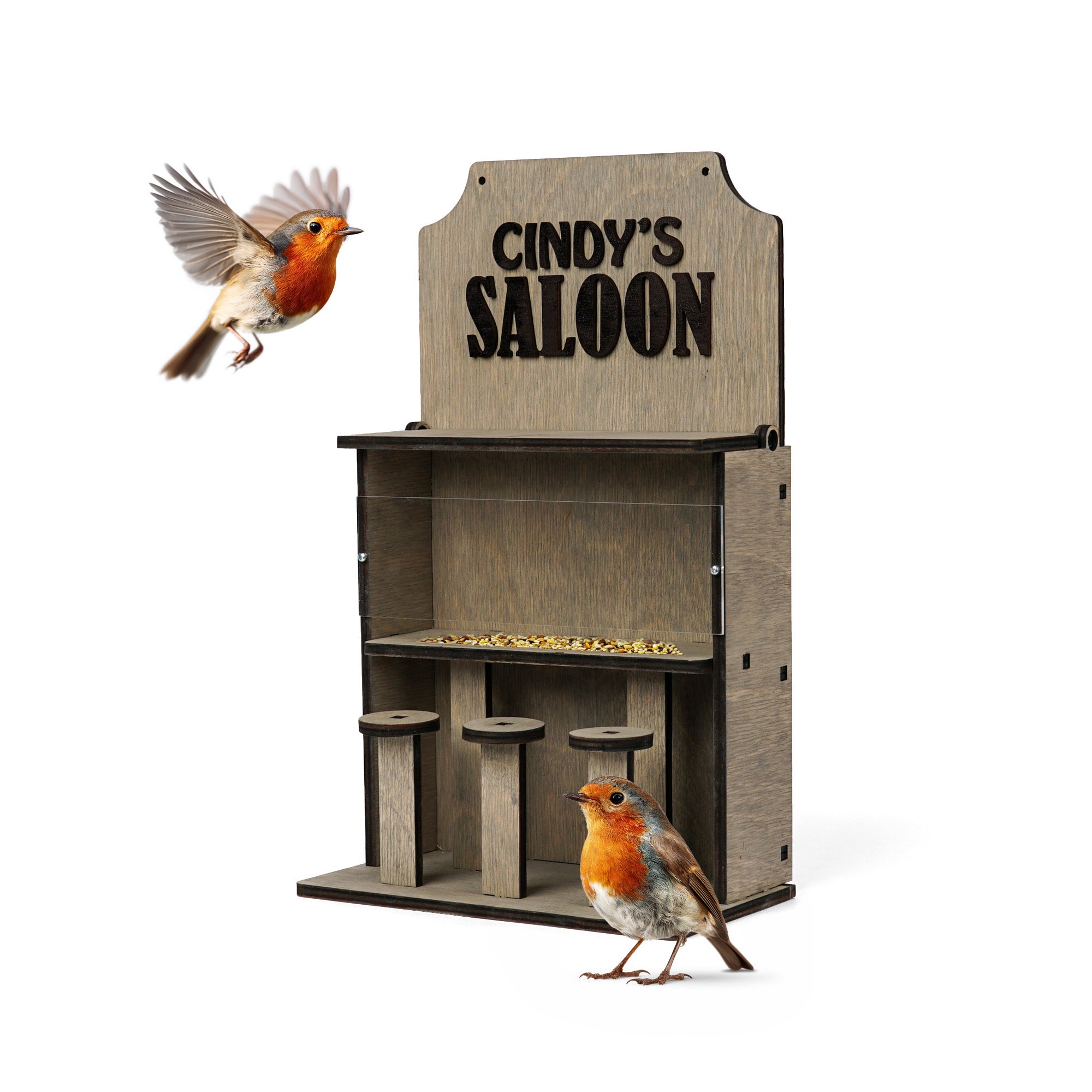 A wooden bird feeder designed to look like a shop counter with a sign reading 'CINDY'S SALOOON', shown on a white background with two robins around it.