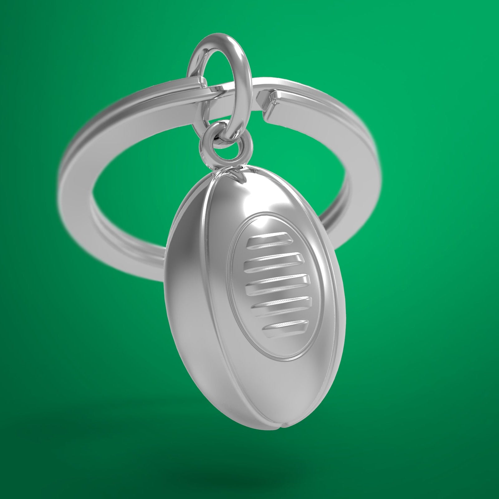 Silver rugby ball keychain on a green background