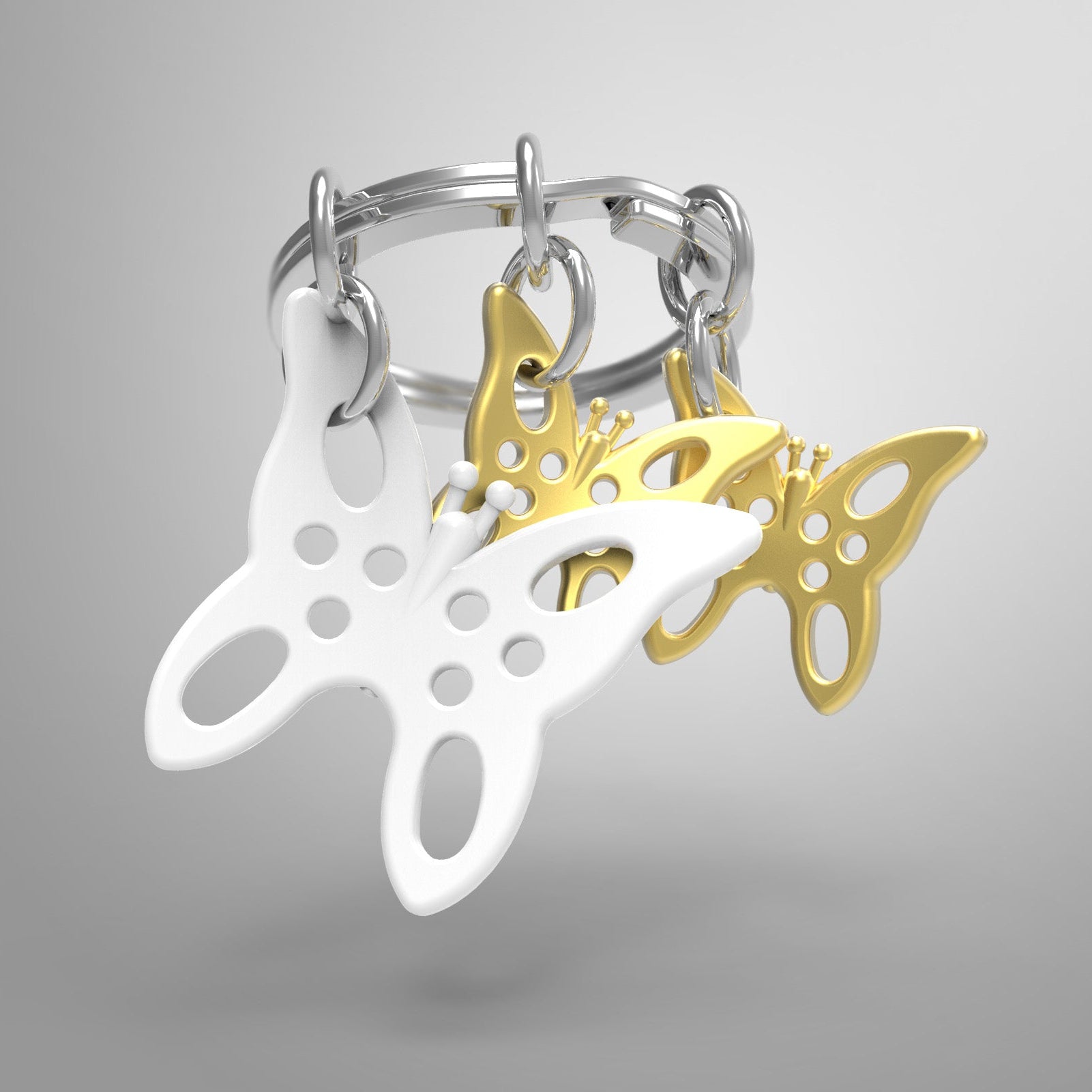 Butterfly-shaped keychains in white and gold on a gray background