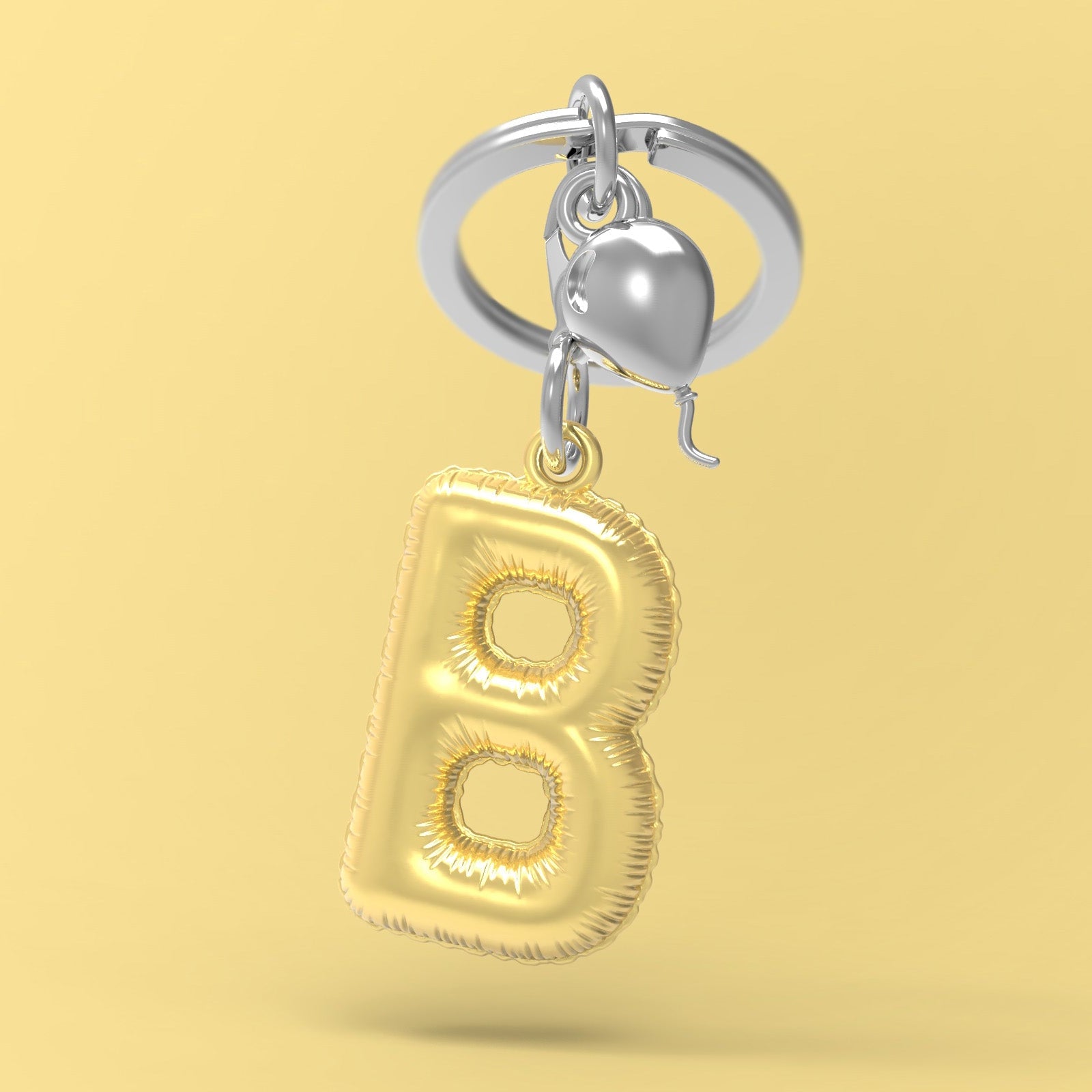 Gold letter 'B' balloon keychain on a yellow background